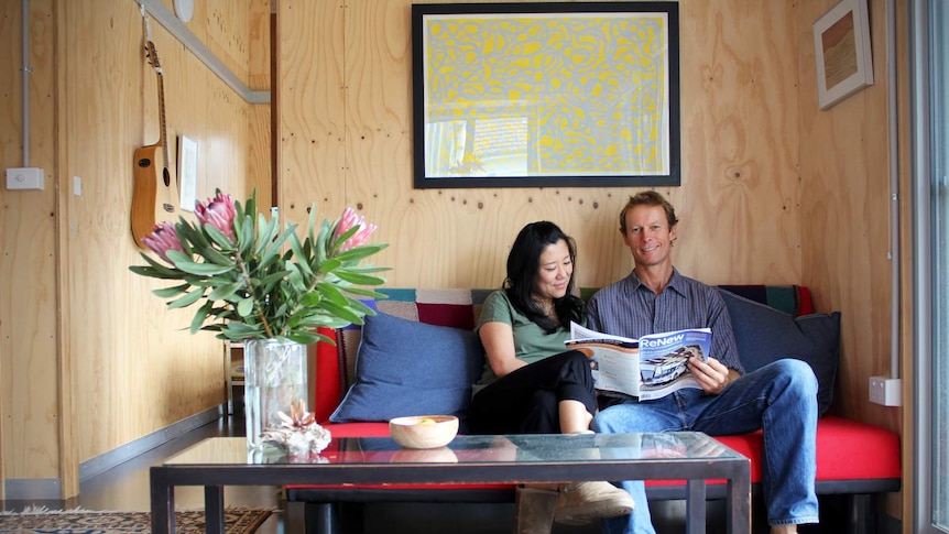 Andy Lemann and his partner Cintia Yamane sit on their couch.