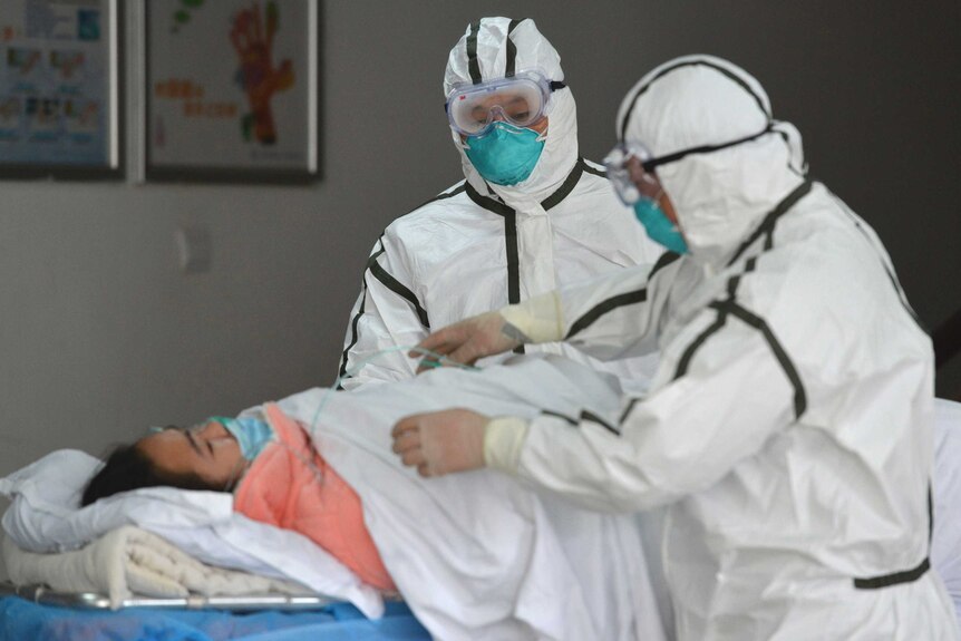 Medical workers in protective suits move a coronavirus patient into an isolation ward.