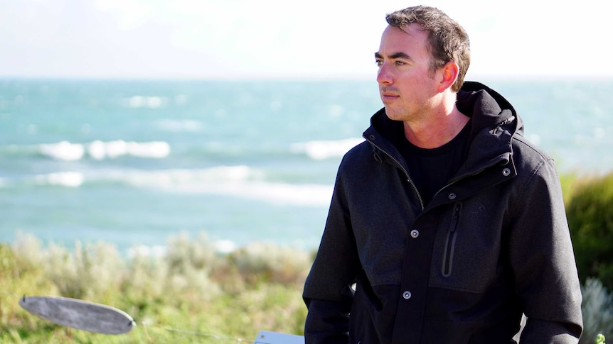 Rick Gerring standing on a hill with the ocean behind him