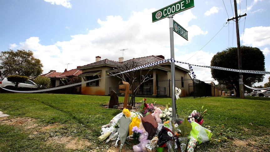 Flowers lie below a street sign outside a house in Coode Street, Bedford, after two women and three children were found dead.