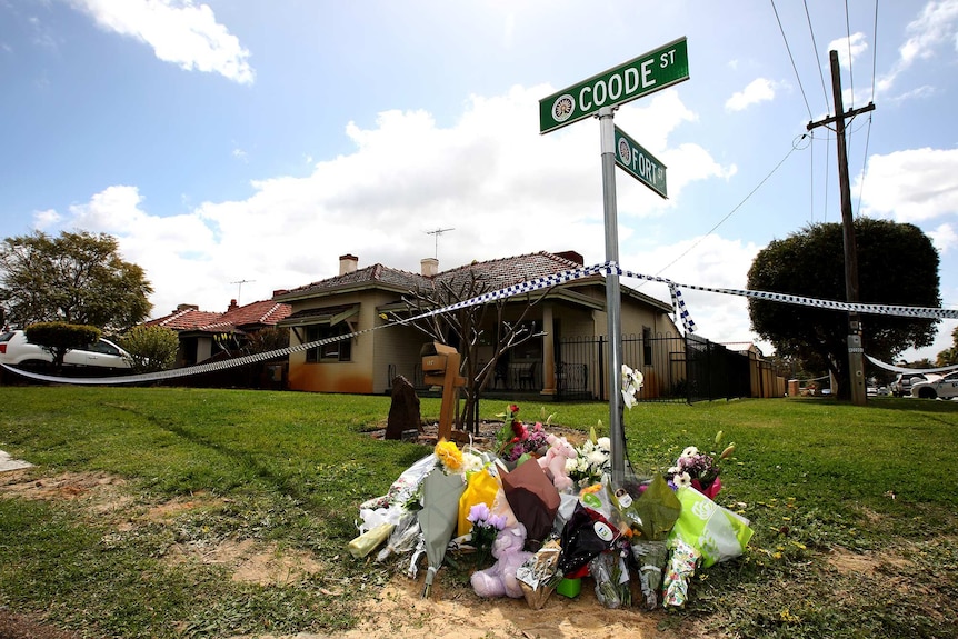 Flowers lie below a street sign outside a house in Coode Street, Bedford, after two women and three children were found dead.