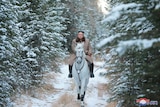 Kim Jong Un riding on white horse among green trees in the snow.