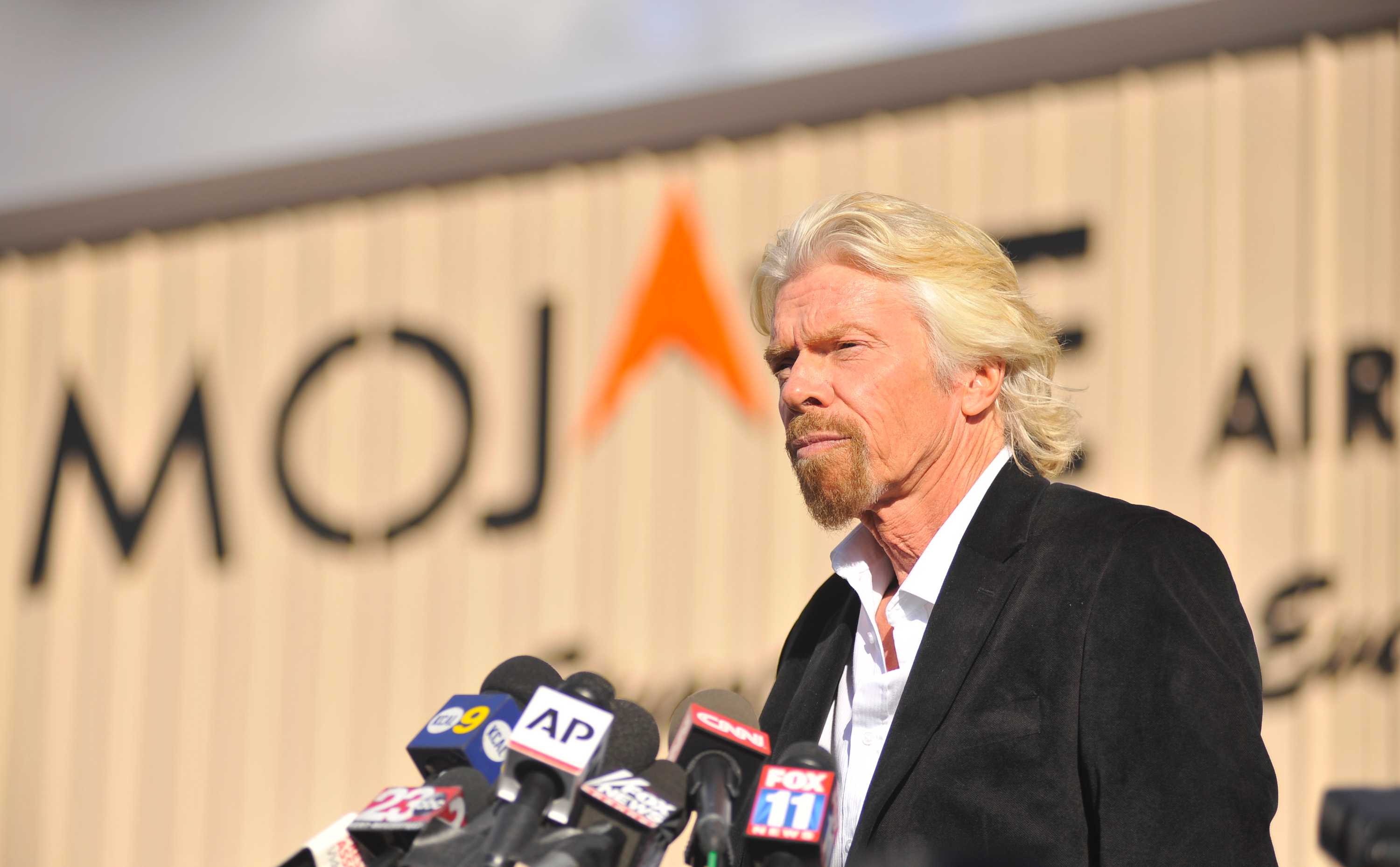 Richard Branson standing at a podium about to do a press conference. 