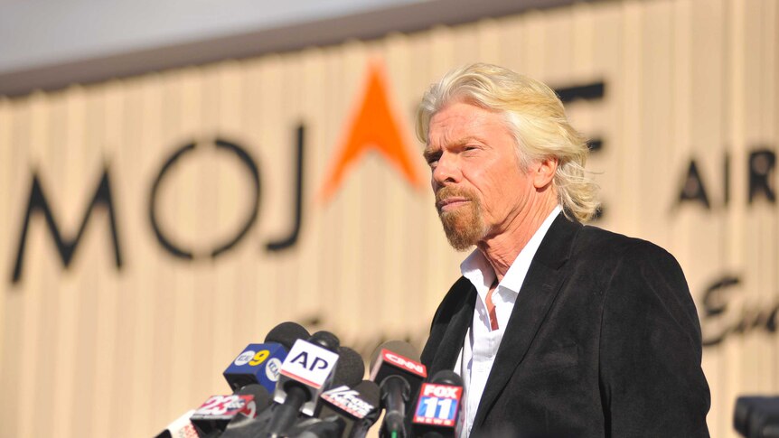 Richard Branson standing at a podium about to do a press conference. 