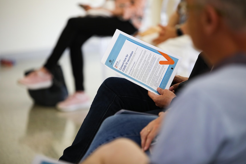 A person holds a COVID-19 vaccination consent form.