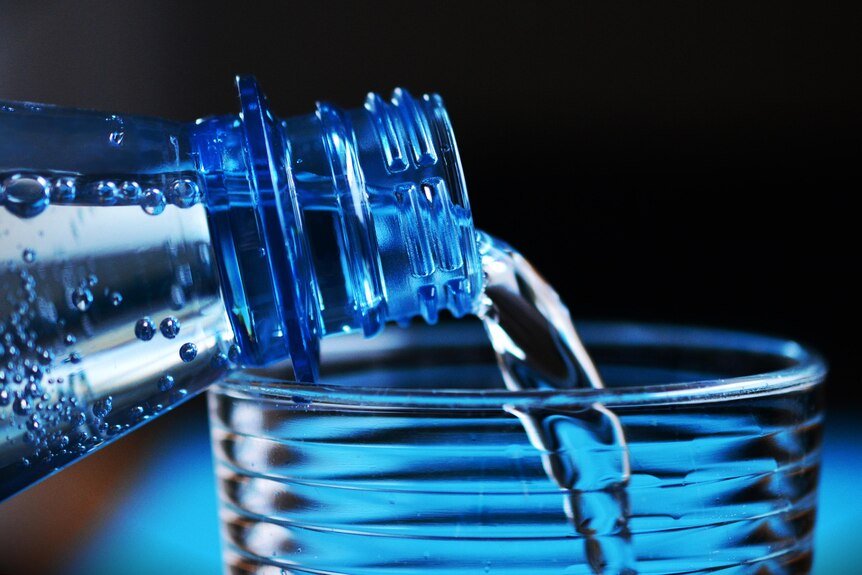 una botella de agua con burbujas que se vierte en un vaso