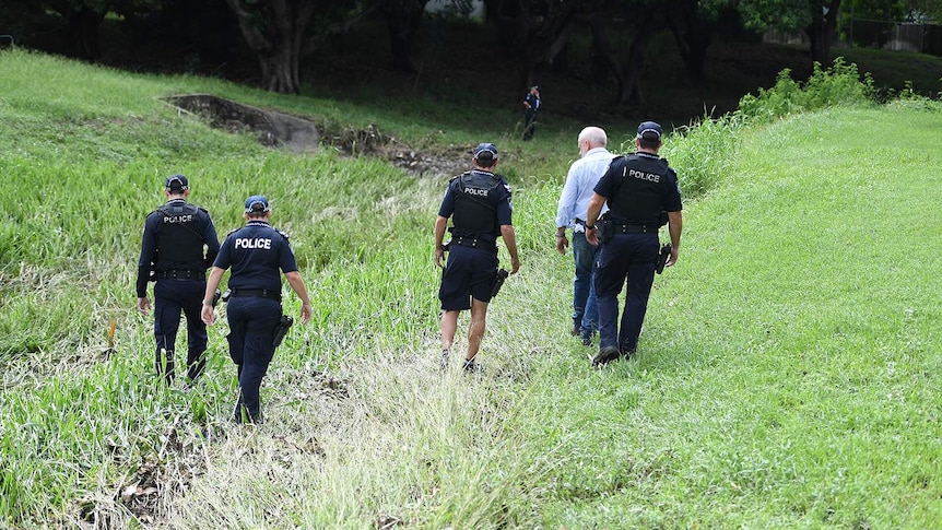 Police search the scene where two bodies were found in a drain.