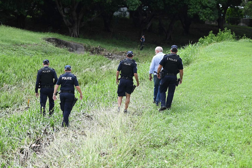 Police search the scene where two bodies were found in a drain.