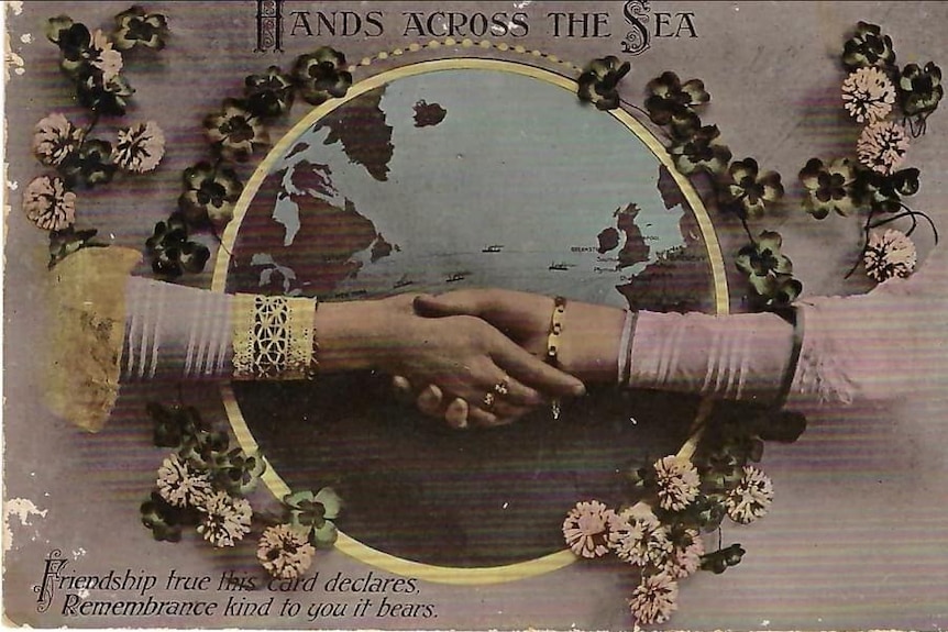 The front of the postcard is pink with flowers and two arms reaching for each other.