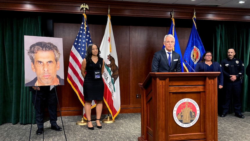 A man at podium, flanked by three other people and various flags, stands beside a photo of a man charged with sexual assault