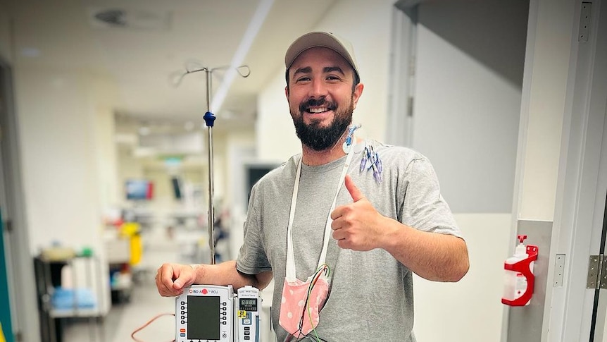 Man stands thumbs up in hopsital