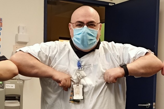 A man wears a surgical mask and surgical gown.