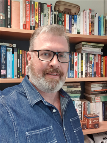 A man stands in front of bookshelves.