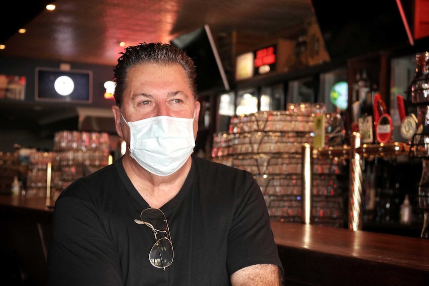 A man wearing a mask in a bar.