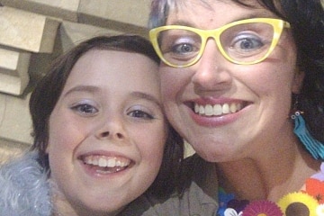 A woman with yellow glasses and a girl smiling close to each other