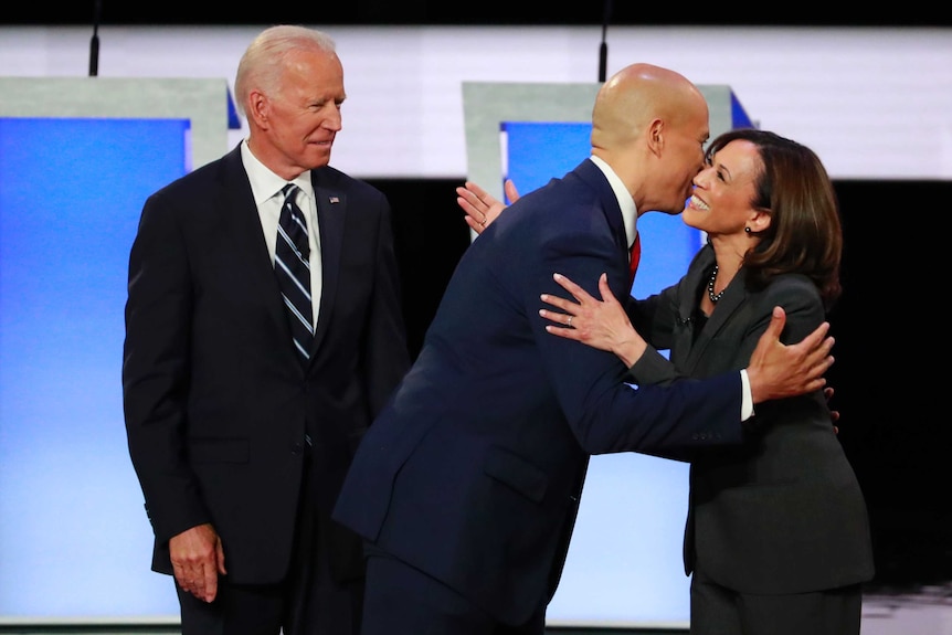 Former Vice President Joe Biden look on as US Senator Cory Booker and US Senator Kamala Harris greet each other