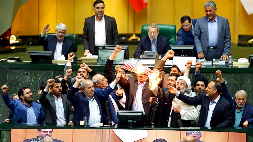 Politicians cheer in Parliament as they burn paper with the US flag on it.