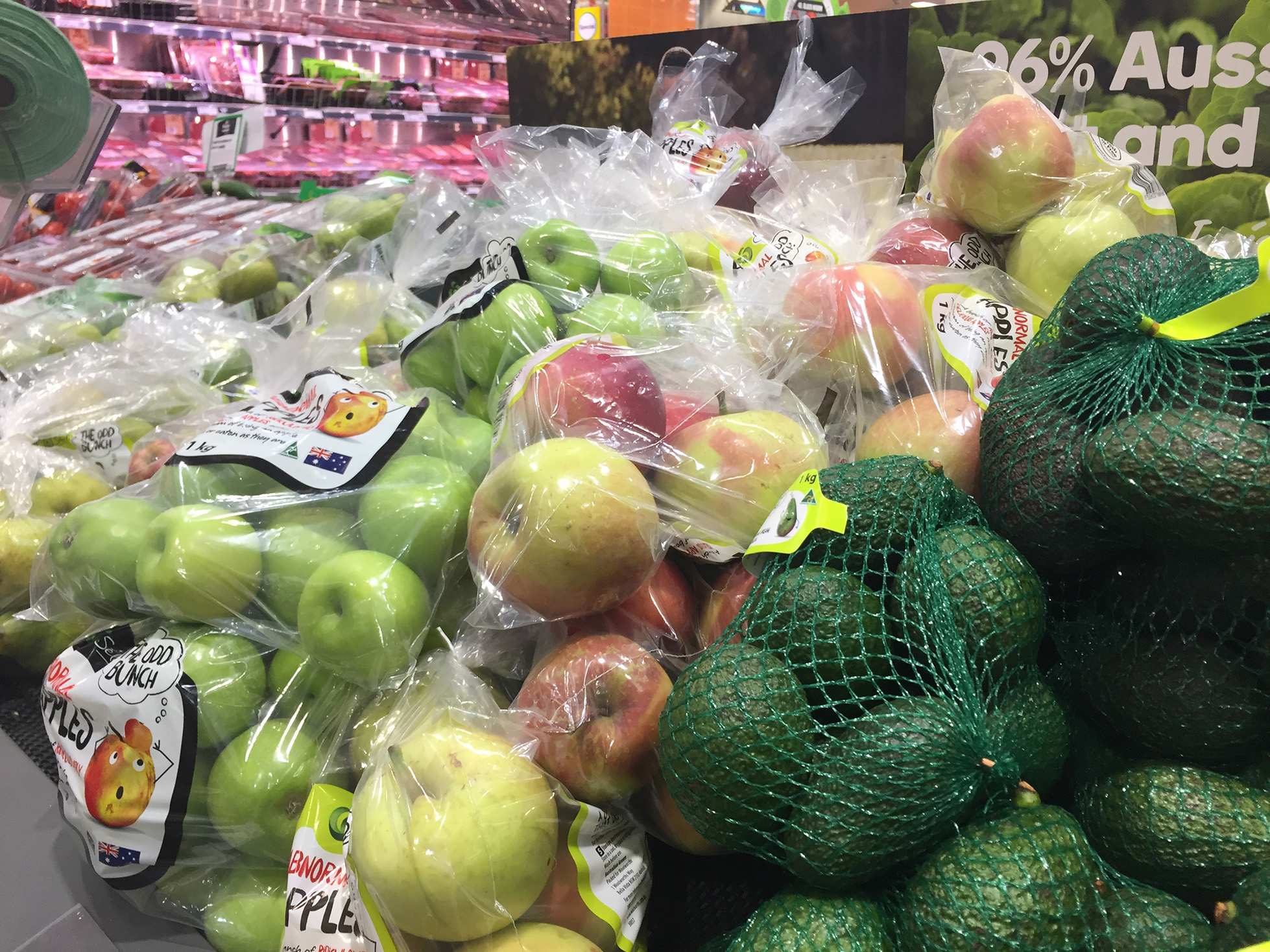 Bunches of apples and avocados wrapped in plastic and fruit netting in the supermarket