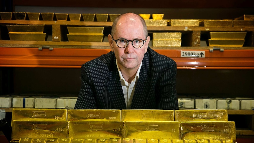 A man standing next to gold bars.