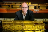 A man standing next to gold bars.