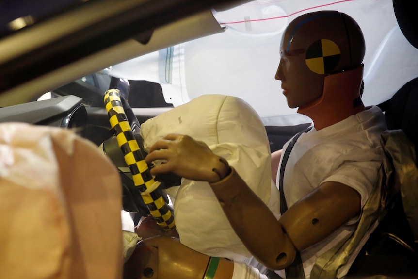 An air bag explodes towards a crash test dummies