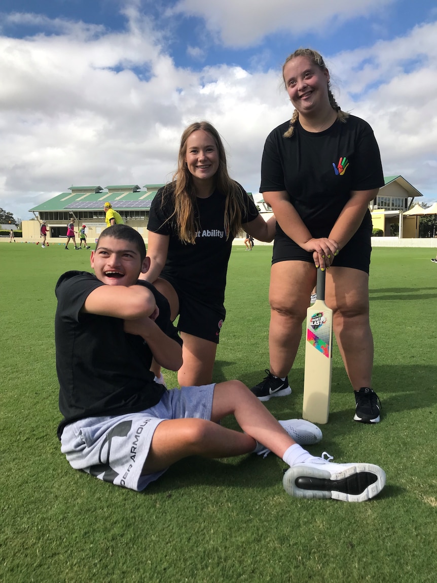 Lauren Cheatle sits with two participants in a cricket clinic.