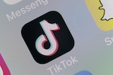 A close up of the TikTok logo on a phone screen. The logo looks like a musical note on a black background.