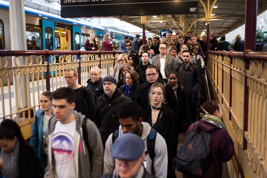 A crowd of passengers exiting a train at Flinders Street station and walking into the subway.