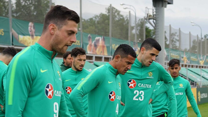 Socceroos players breathe in deep and look downwards during intense training session.