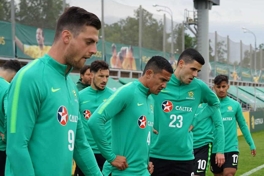 Socceroos players breathe in deep and look downwards during intense training session.