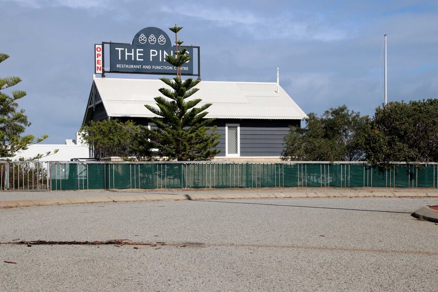 A carpark with a dark stain on the ground with The Pines function centre in the background.