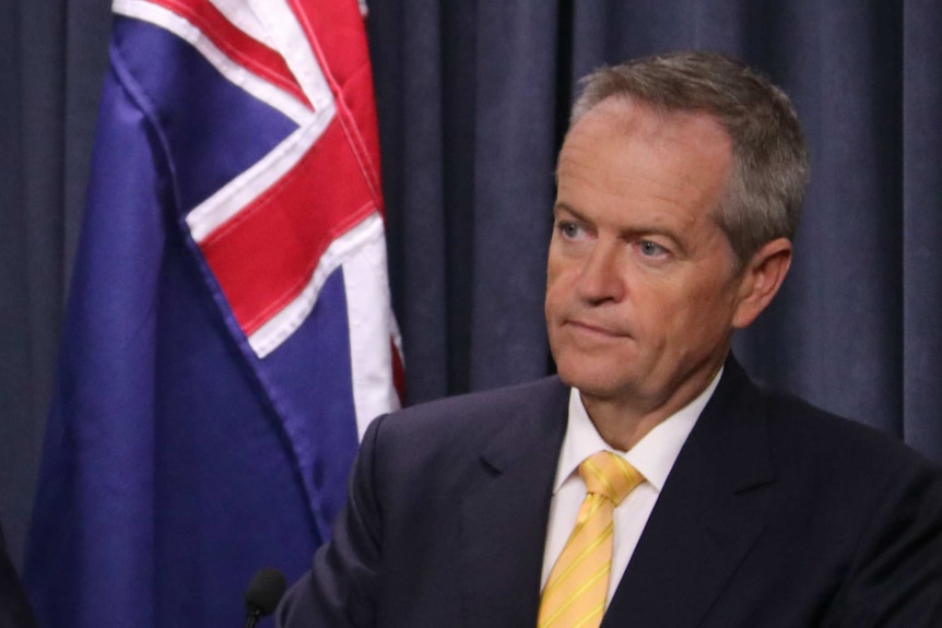 Bill Shorten standing in front of an Australian flag.