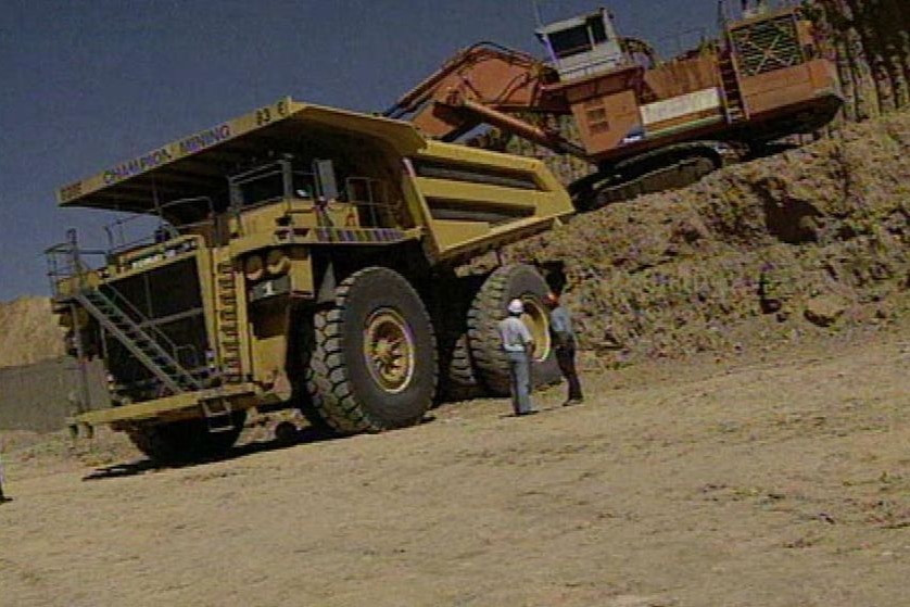 Workers at a mining site with a truck and excavator at an unidentified location in central-west Qld.