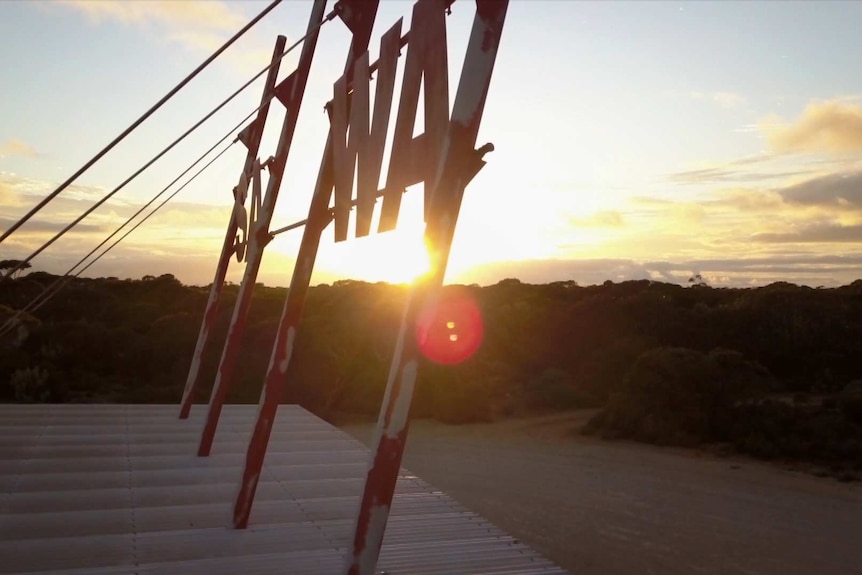 The WA-SA border checkpoint sign, with the sun rising in the background.