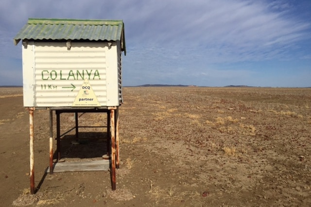 Colanya station sign with droughted land in the backdrop.