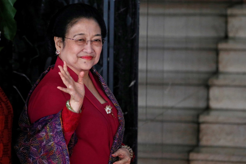 Former Indonesian President Megawati Soekarnoputri waves to reporters.