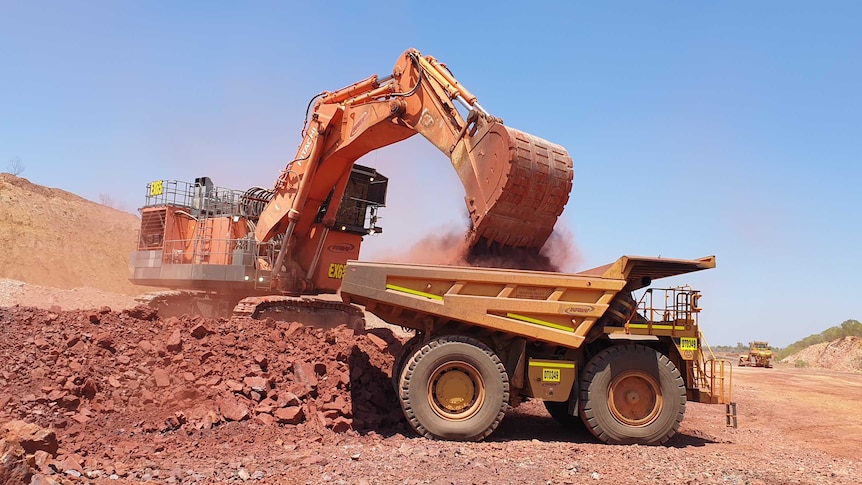 A digger is filling up a truck with iron ore in the NT.