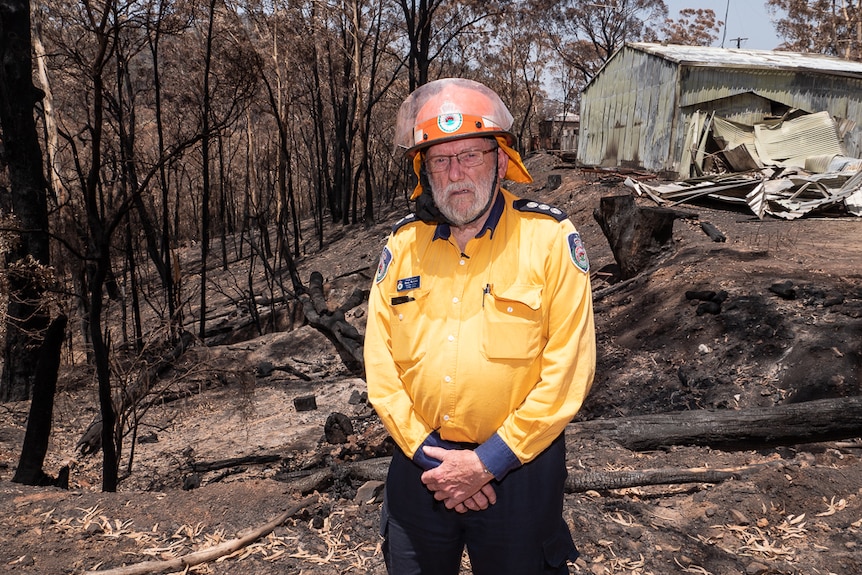 Firefighter Barry Richard looks at the camera with a fire-damaged shed and bushland in the background