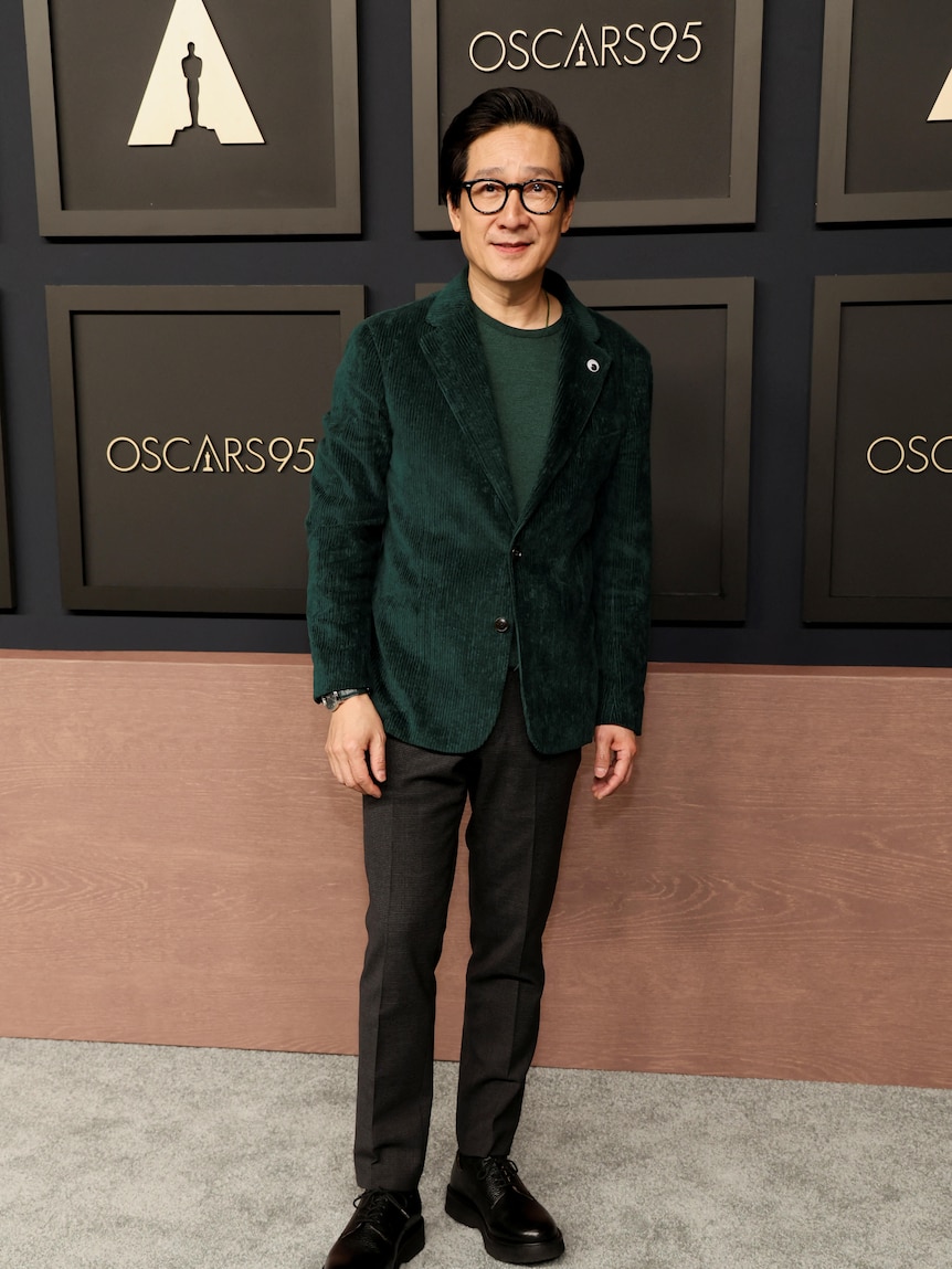 Ke Huy Quan in a green velvet suit jacket on the red carpet. 