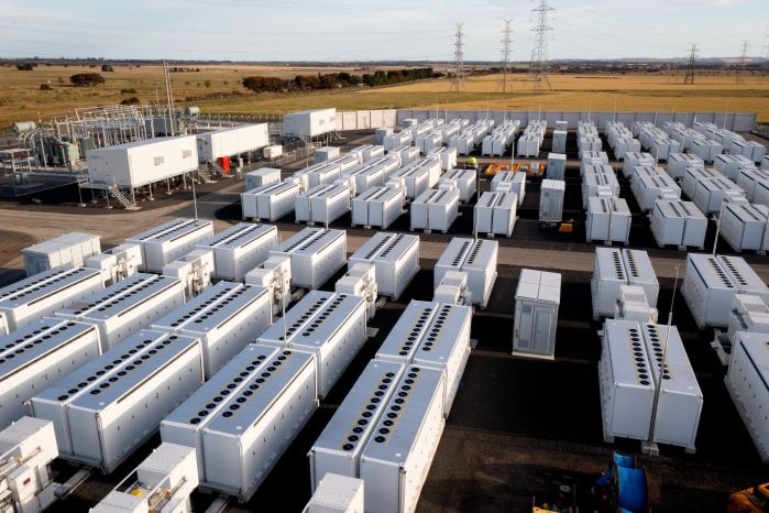 Aerial shot of large-scale battery facility, which dozens of big white containers in a field