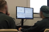 two inmates, with their faces blurred, work at a computer on a University assignment