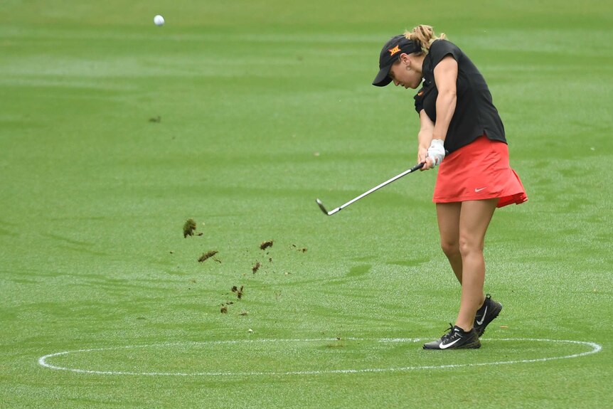 A female golfer plays a shot.