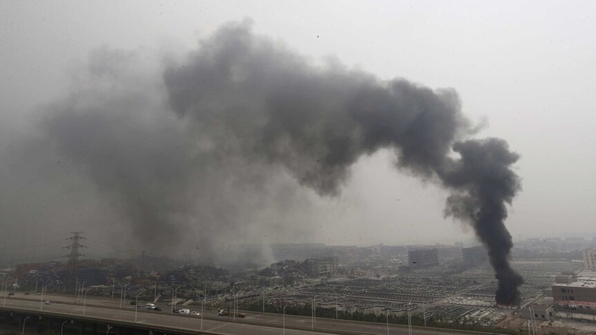 Smoke rises as damaged vehicles are seen burning near the site of the explosions in China