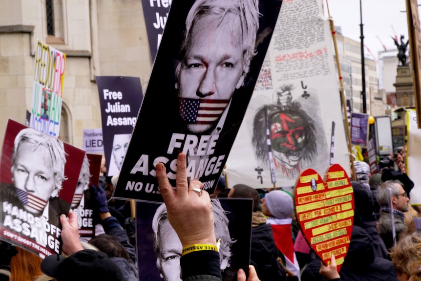 Eine große Menschenmenge hält Schilder mit unterstützenden Parolen für Julian Assange