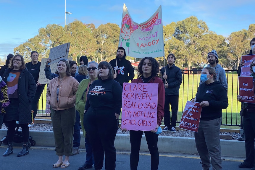 A group of mainly women holding protest signs