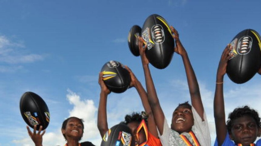 Indigenous children cheering and holding AFL balls