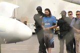 Terror-accused in custody being led onto a plane.