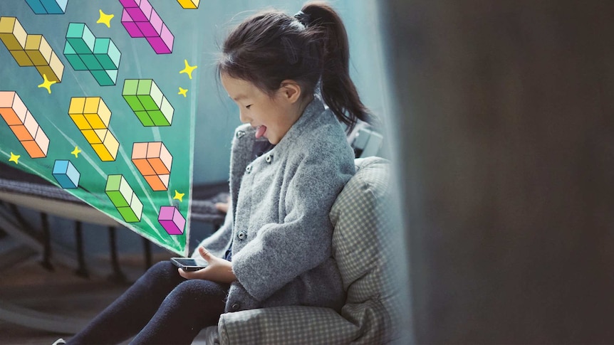 Little girl plays with phone with graphics of tetris coming out of it