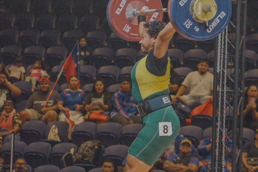 Eileen Cikamatana attempts to lift heavy weights on stage at the Oceania Olympics qualifiers 