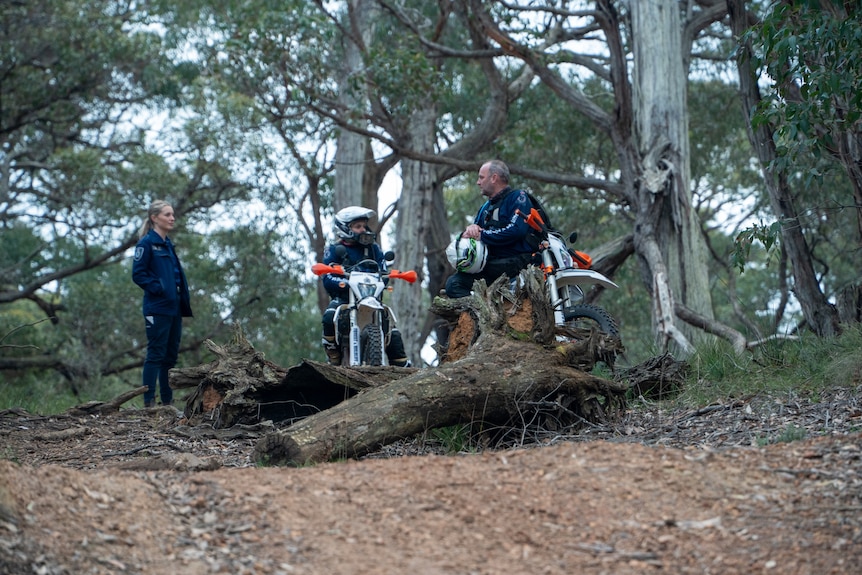 People in uniform on dirt bikes in the bush.